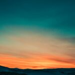 Capture of a stunning twilight sky with colorful gradients over gentle hills.